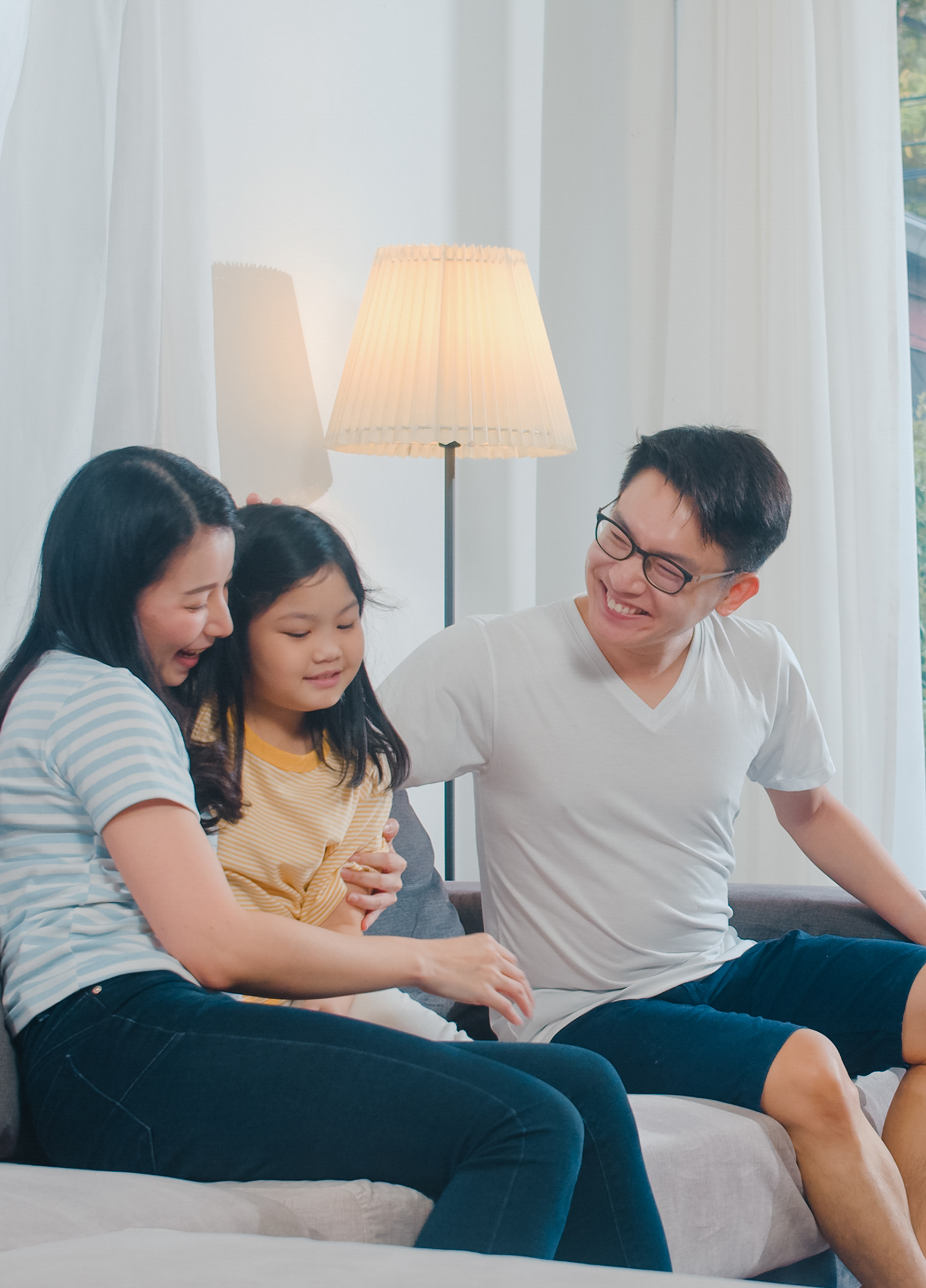 Happy young Asian family play together on couch at home. Chinese